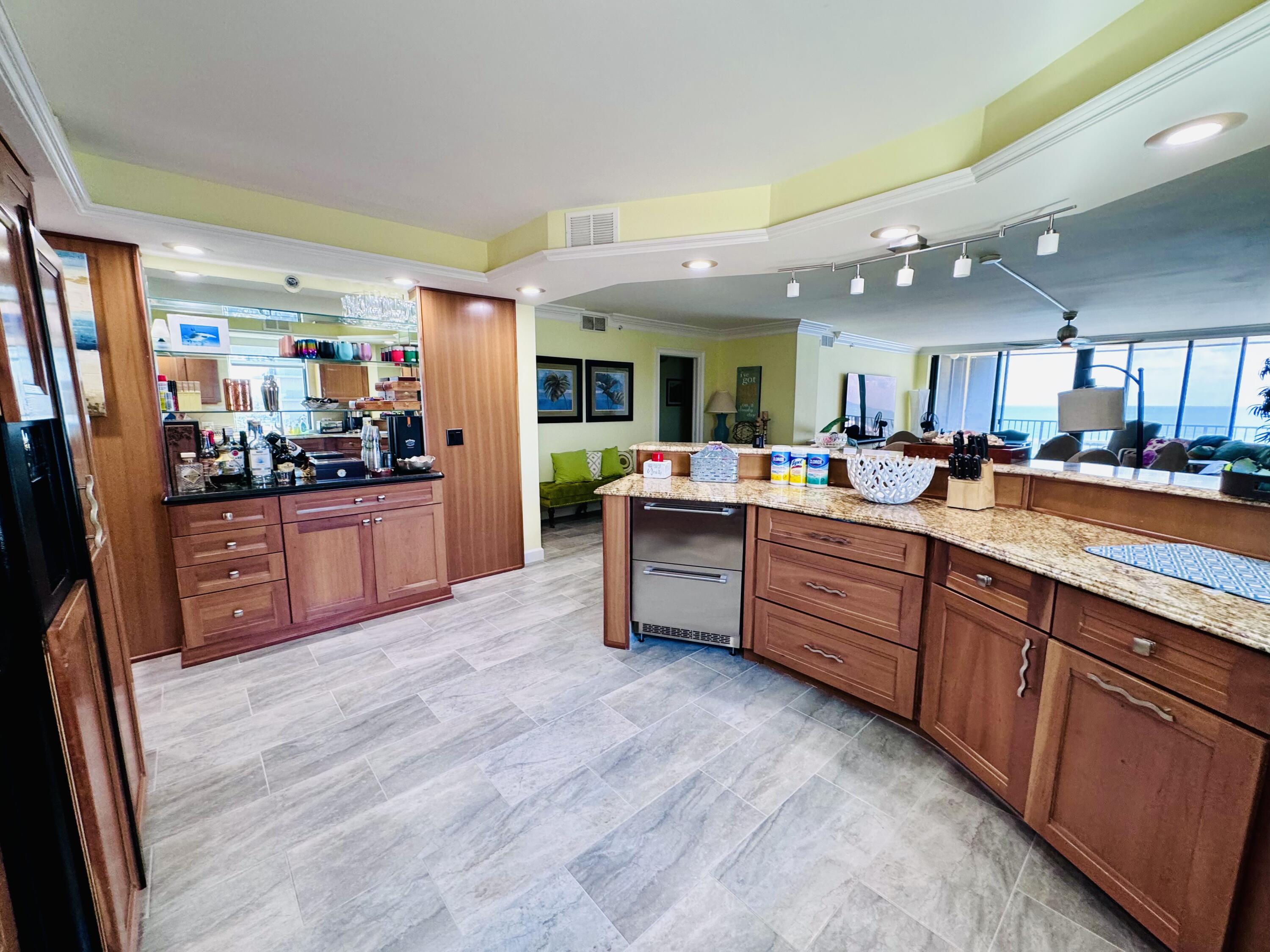 200 South Beach Road, Unit 403 Tequesta, FL 33469 - Photo 8 of 46 a kitchen with stainless steel appliances kitchen island granite countertop wooden cabinets and granite counter tops