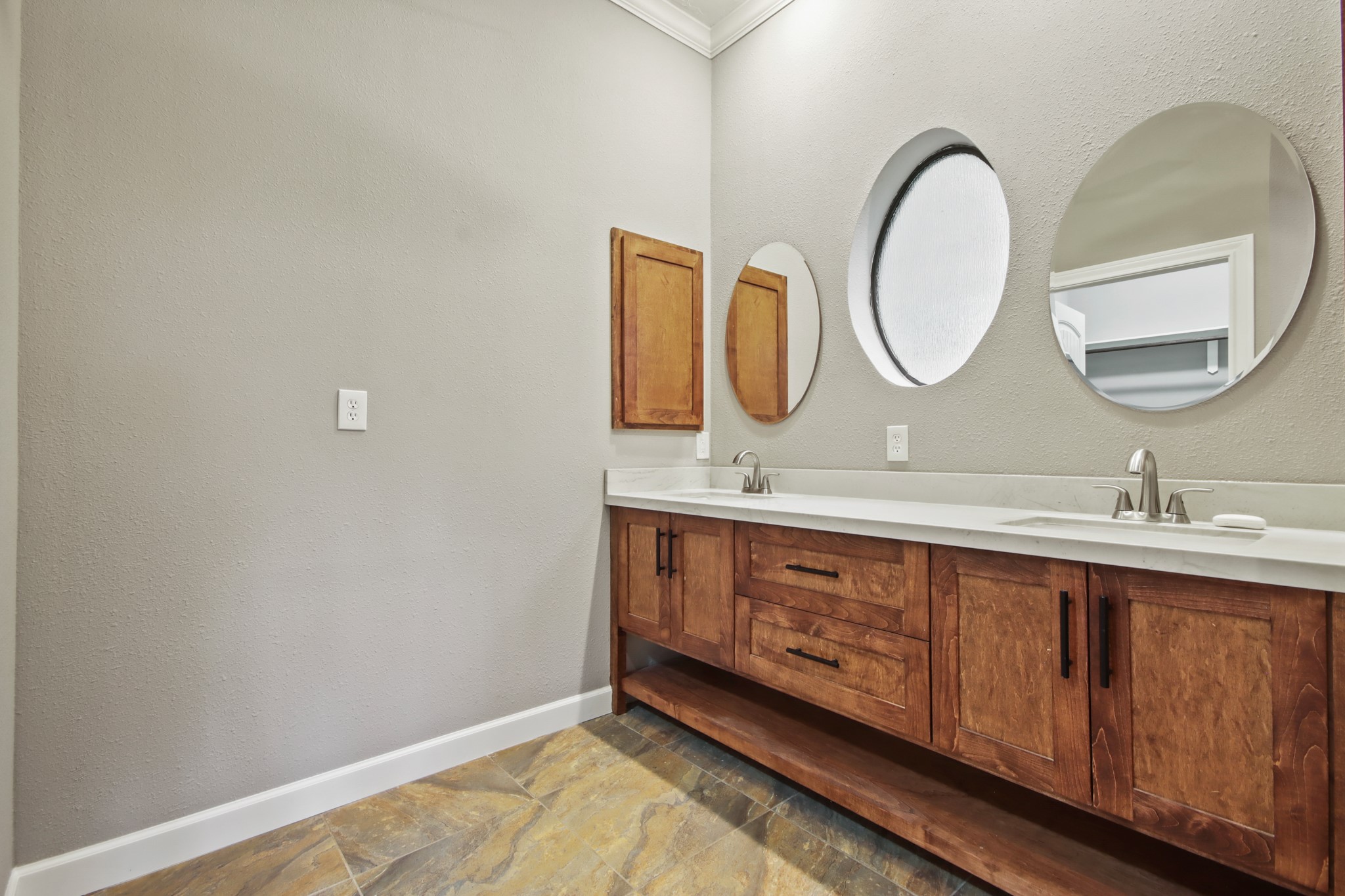 35 Susan Drive Cleveland, TX 77327 - Photo 11 of 33 This bathroom features a double vanity with sleek sinks and stylish round mirrors. The wooden cabinetry adds warmth, while the neutral wall and tile colors create a modern, inviting atmosphere.