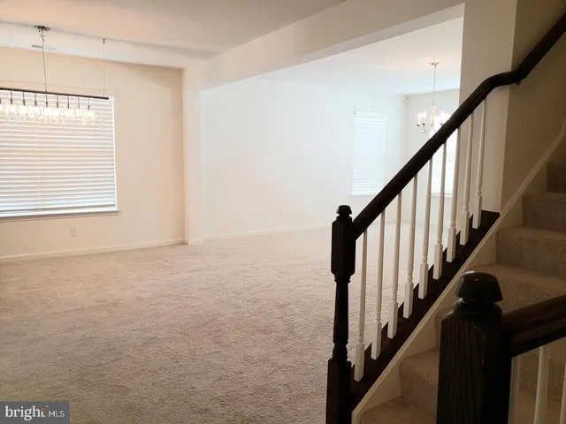 a view of an empty room with wooden floor and stairs