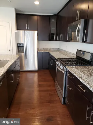 a kitchen with stainless steel appliances granite countertop a refrigerator a stove and a sink