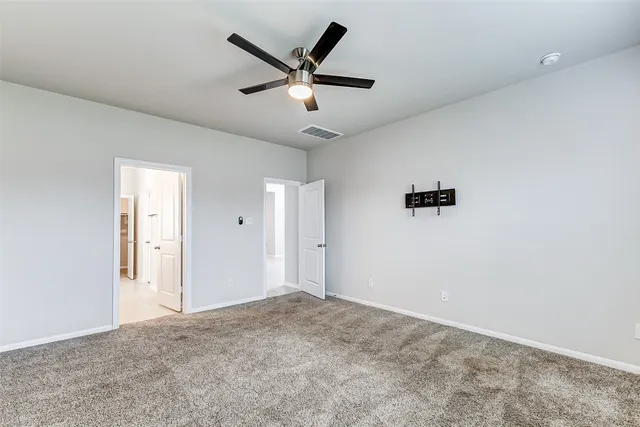 a view of a livingroom with a ceiling fan & windows