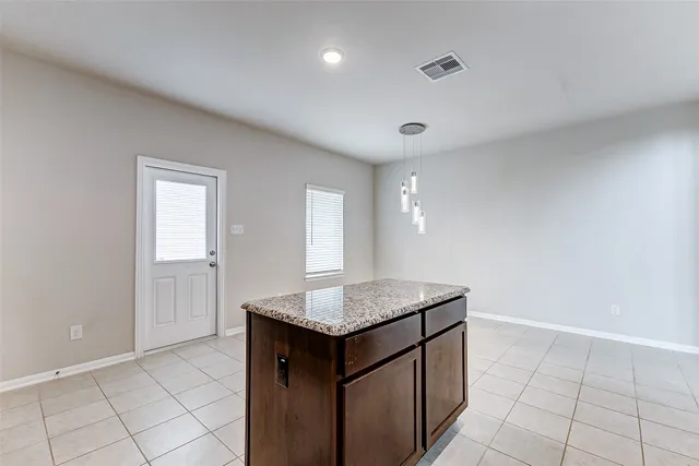 a hallway with granite countertop cabinets and chandelier