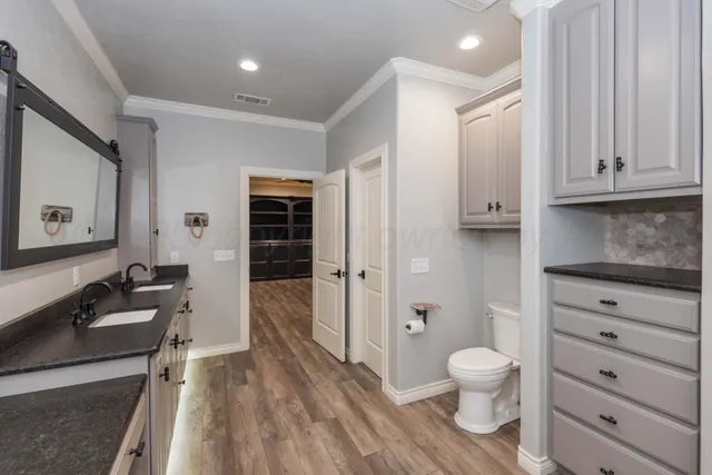 a view of an empty room with wooden floor and a ceiling fan