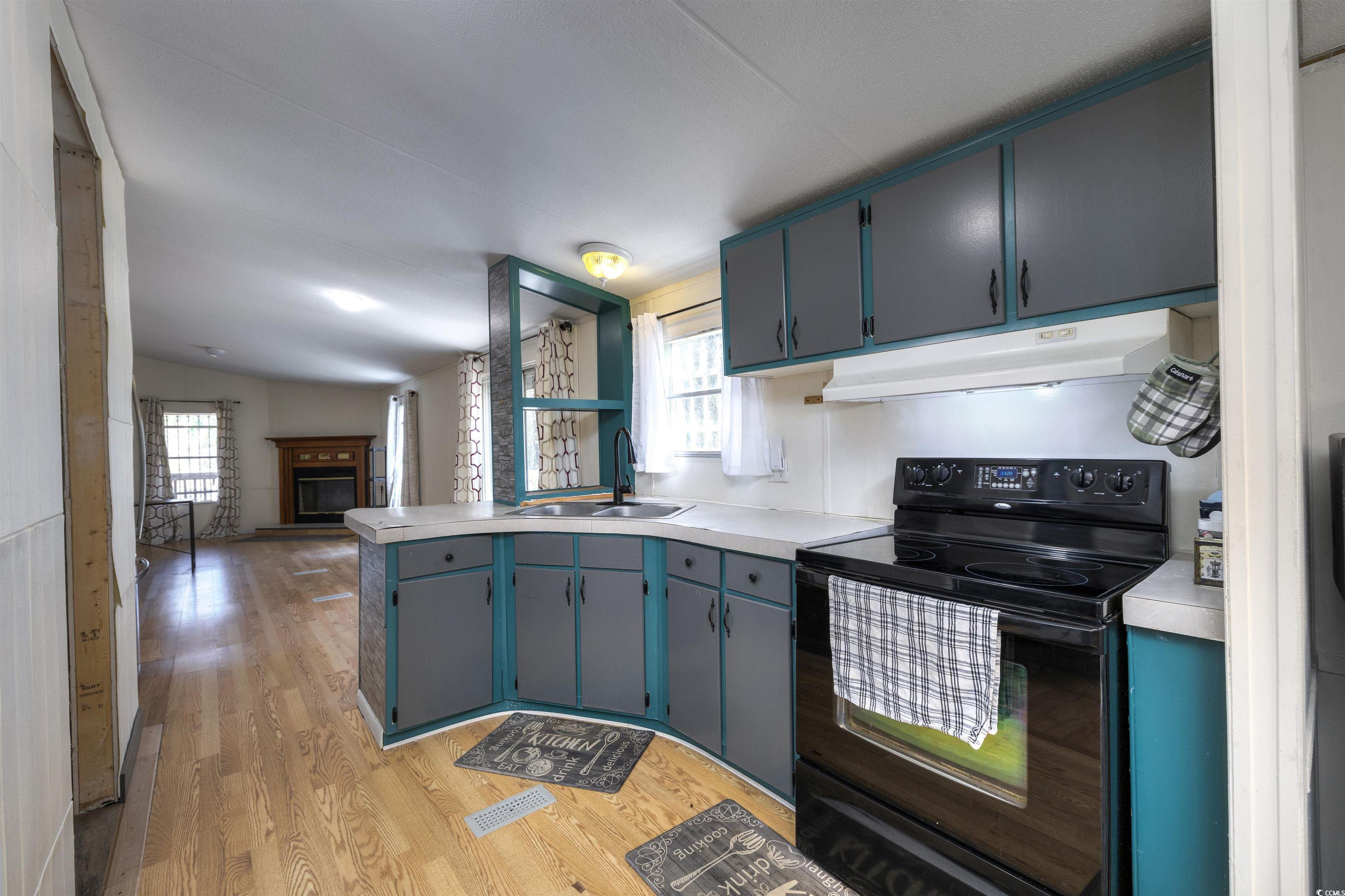 5764 Thompson Road Nichols, SC 29581 - Photo 8 of 35 Kitchen featuring blue cabinetry, black range with electric stovetop, under cabinet range hood, a peninsula, and a sink