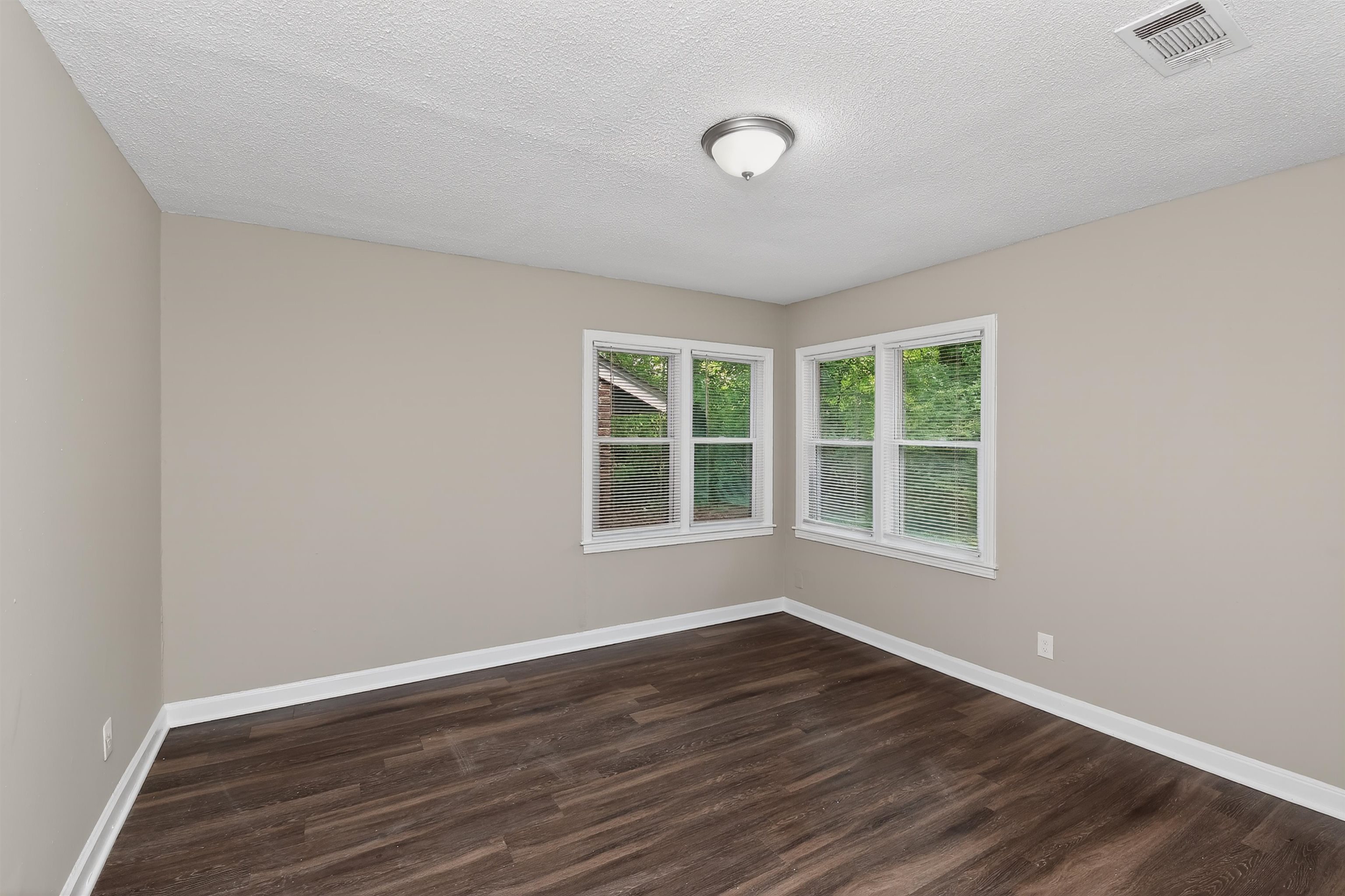 318 East Raines Road Memphis, TN 38109 - Photo 13 of 28 Room featuring wood-finish flooring, two large windows, neutral wall paint, white trim, and a ceiling-mounted light fixture