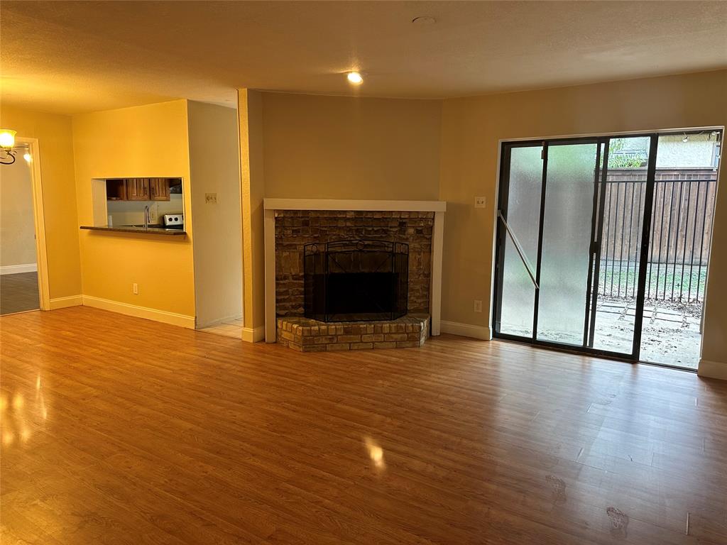 336 Melrose Drive, Unit 7B Richardson, TX 75080 - Photo 8 of 18 Unfurnished living room featuring wood finished floors, a fireplace with raised hearth, and a chandelier