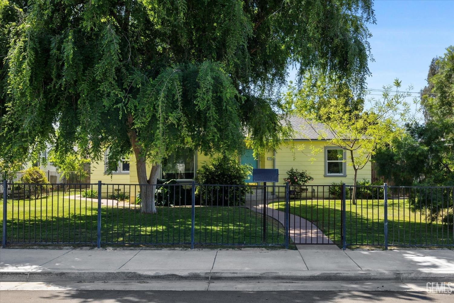 Undisclosed Address Bakersfield, CA 93305 - Photo 2 of 39 a view of a white house in front of a yard with plants and large trees