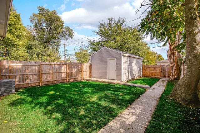 a view of a backyard with large trees and wooden fence
