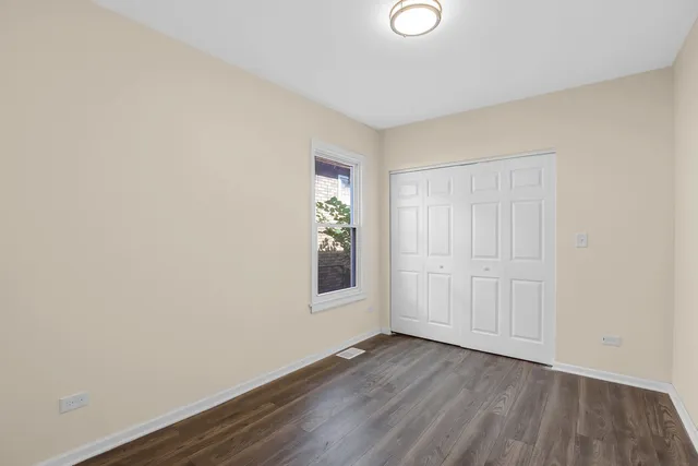 a view of an empty room with wooden floor and closet