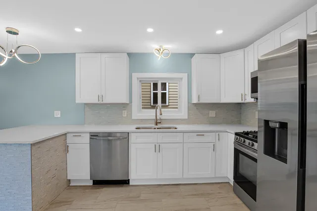 a kitchen with stainless steel appliances granite countertop a stove a sink and white cabinets