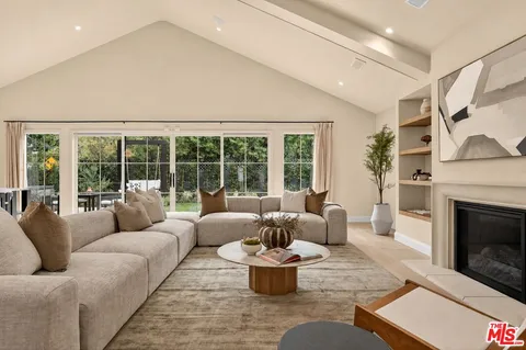 a large kitchen with a counter space a sink appliances and living room view