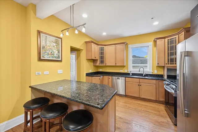 a kitchen with stainless steel appliances granite countertop a sink a stove and a refrigerator