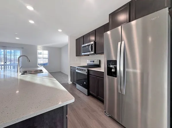 a kitchen with stainless steel appliances granite countertop a refrigerator a stove and a sink with wooden floor