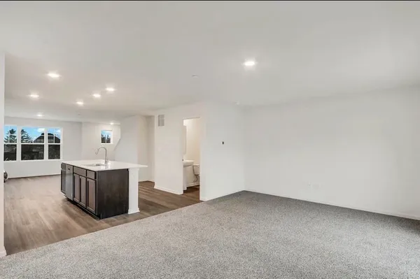 an empty room with wooden floor and kitchen