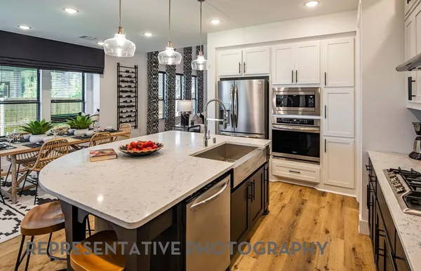 a kitchen with stainless steel appliances a dining table chairs stove and refrigerator