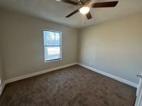 an empty room with a window and a fan