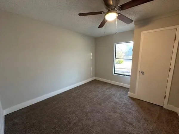 an empty room with a window and a fan