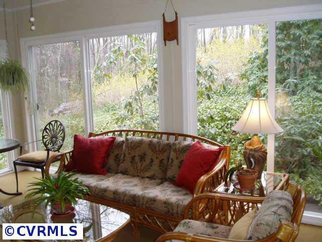 Other - Florida room with exposed painted brick wall, carpet, ceiling fan and door leading to patio and gardens