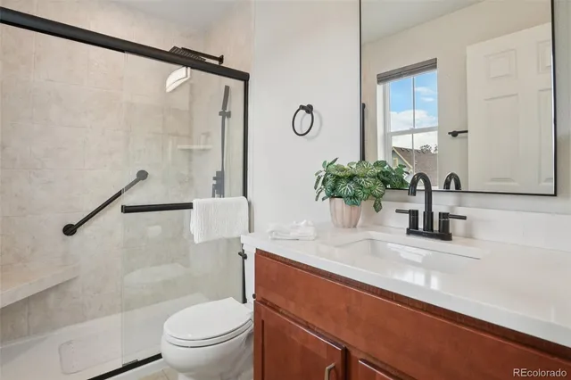 a bathroom with a granite countertop sink a toilet a mirror and shower