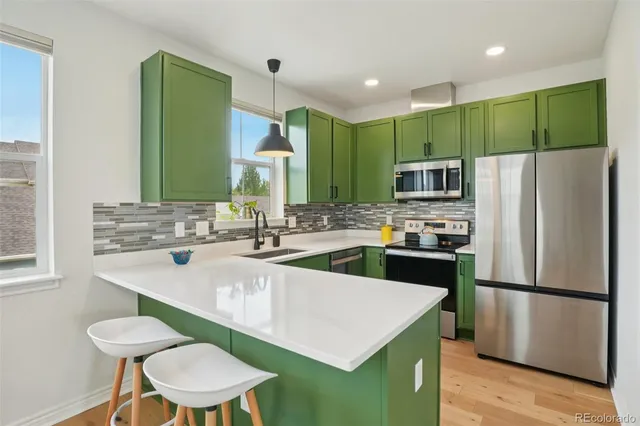 a kitchen with a sink a kitchen island a refrigerator and a stove