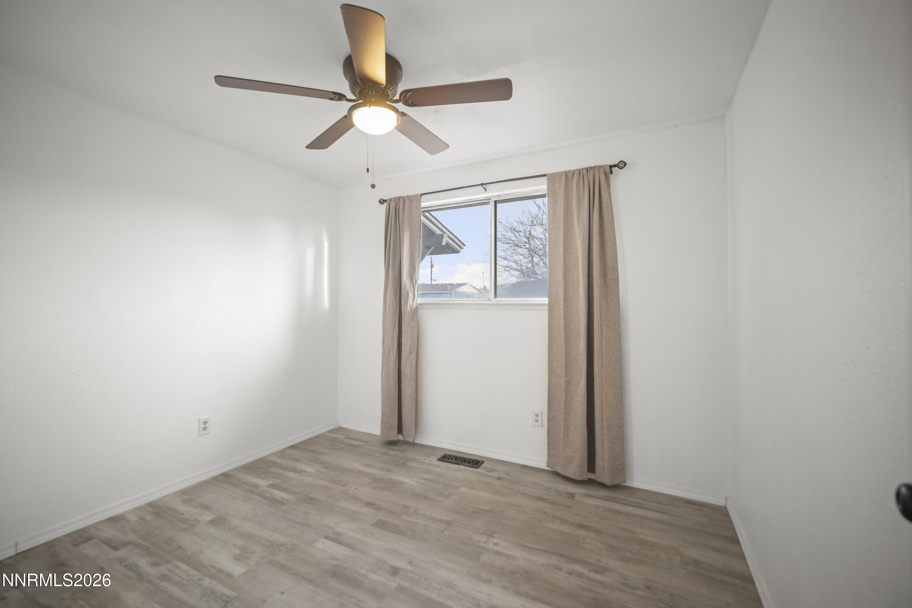 150 McCart Street Fernley, NV 89408 - Photo 12 of 28 an empty room with a window and a fan