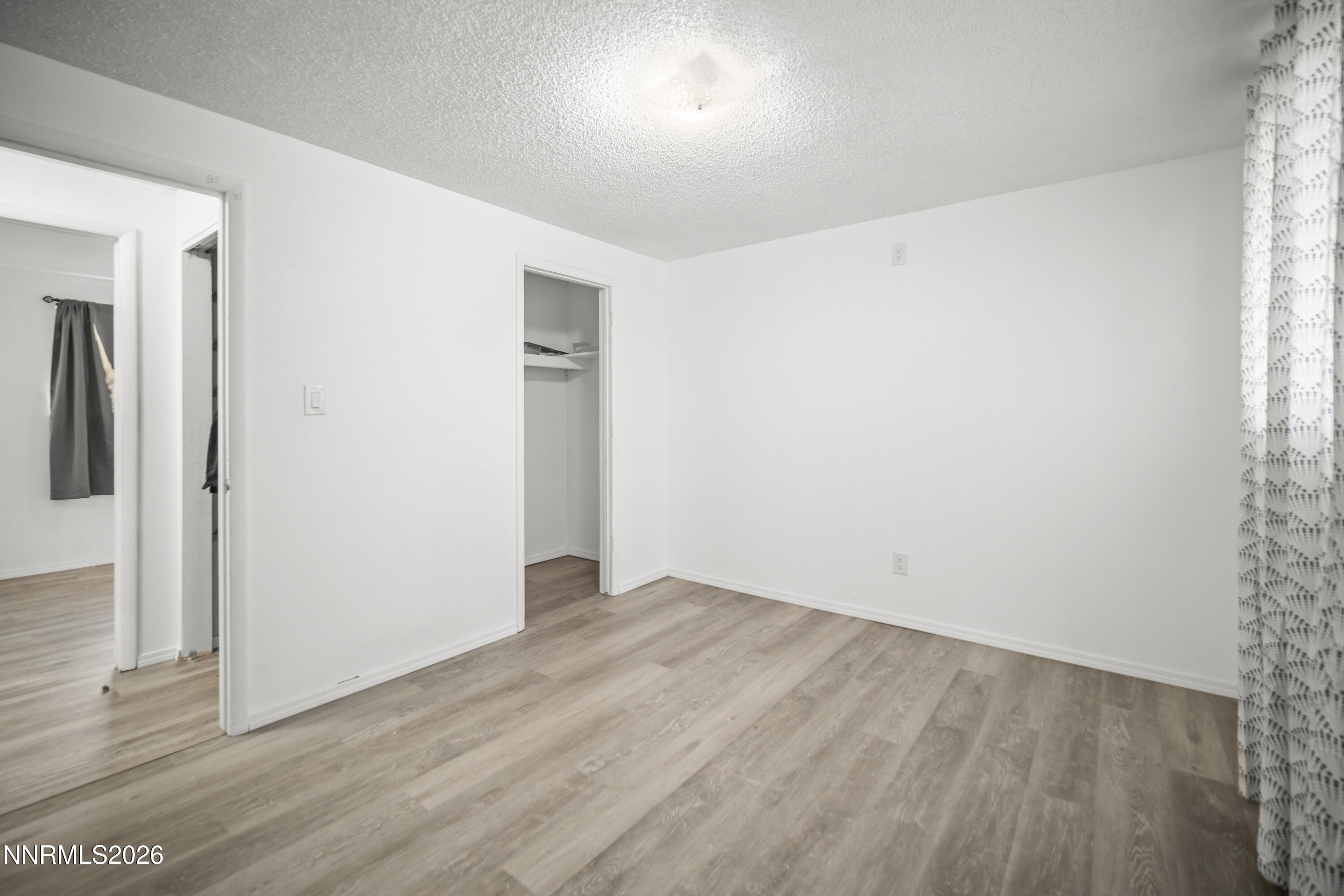 150 McCart Street Fernley, NV 89408 - Photo 19 of 28 an empty room with wooden floor and windows