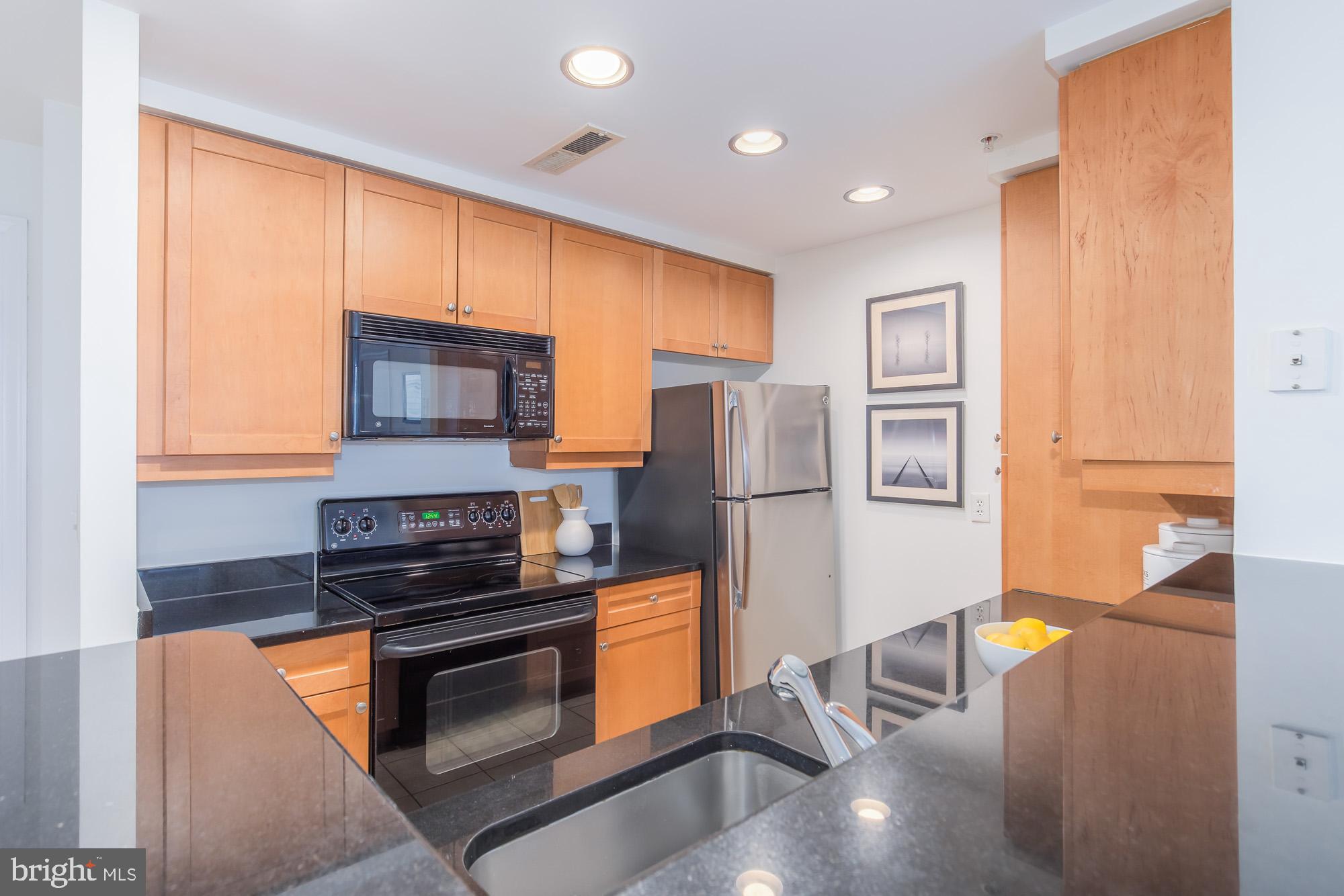 1111 11th Street Northwest, Unit 309 Washington, DC 20001 - Photo 10 of 18 a kitchen with stainless steel appliances granite countertop a refrigerator a stove and a sink with cabinets