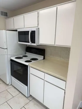 a kitchen with stainless steel appliances white cabinets and a refrigerator