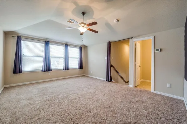 a view of an empty room with chandelier fan and a window