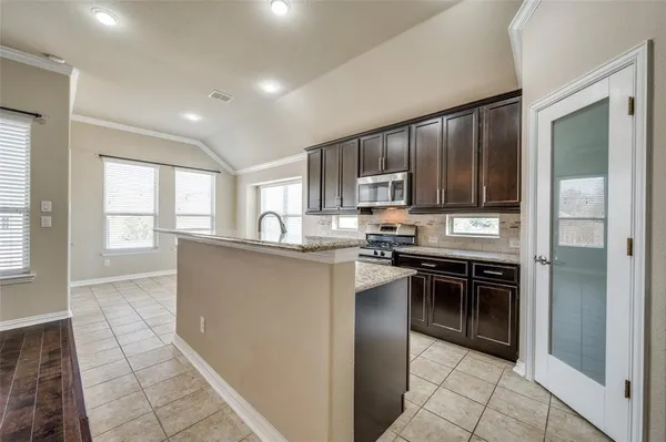 a kitchen with kitchen island granite countertop a stove refrigerator and cabinets