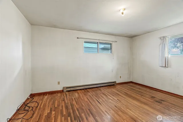 a view of an empty room with wooden floor and a window