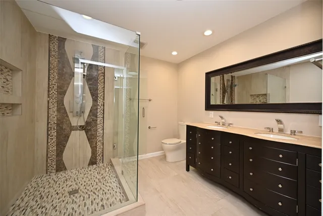 a bathroom with a double vanity sink toilet and shower