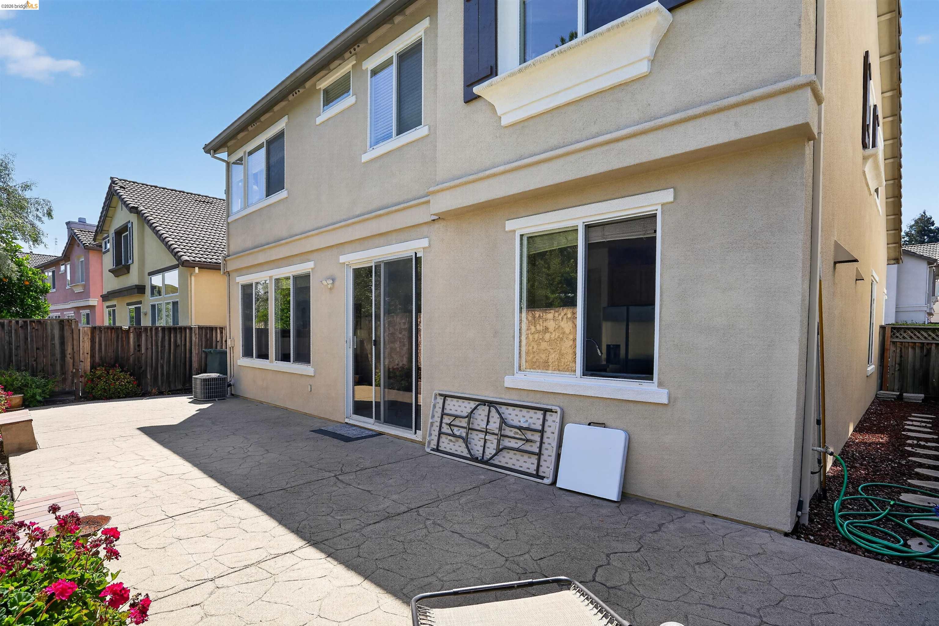 1221 Andrea Way Vallejo, CA 94591 - Photo 27 of 29 Stucco exterior with multiple windows, featuring a sliding glass door and a patterned concrete patio