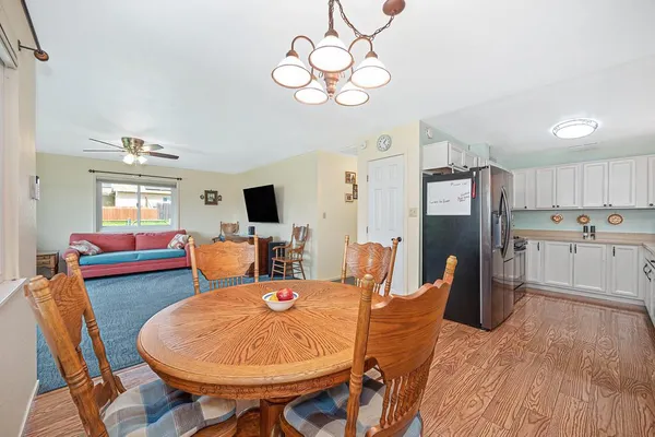 a dining room with wooden floor a chandelier a glass table and chairs