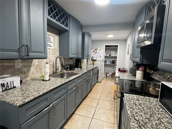 a large kitchen with granite countertop lots of counter space and stainless steel appliances