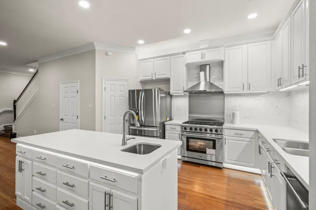 a large white kitchen with center island and stainless steel appliances