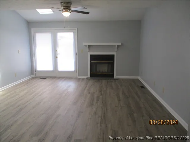 an empty room with wooden floor fireplace and windows