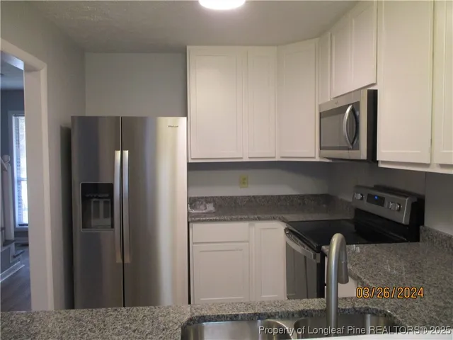 a kitchen with stainless steel appliances granite countertop a refrigerator and a stove top oven