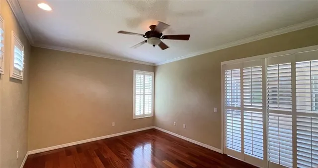 a view of empty room with wooden floor and fan