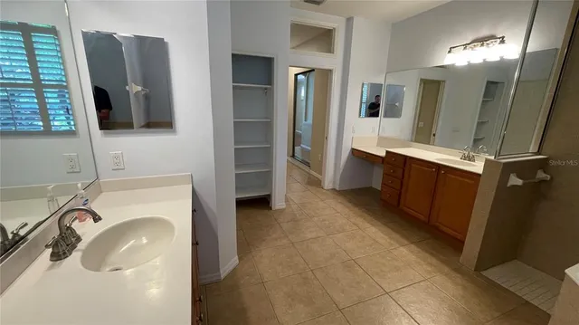 a spacious bathroom with a double vanity sink a mirror and a shower