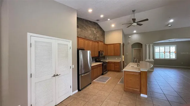 a kitchen with stainless steel appliances kitchen island granite countertop a refrigerator and a sink