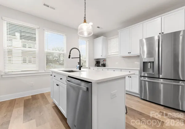 a kitchen with kitchen island granite countertop a sink cabinets a refrigerator and a stove