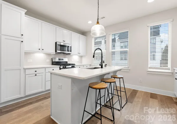 a kitchen with stainless steel appliances granite countertop a stove a sink dishwasher a microwave oven a stove with white cabinets and wooden floor