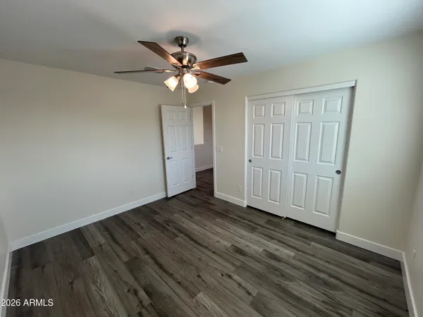 an empty room with wooden floor fan and windows