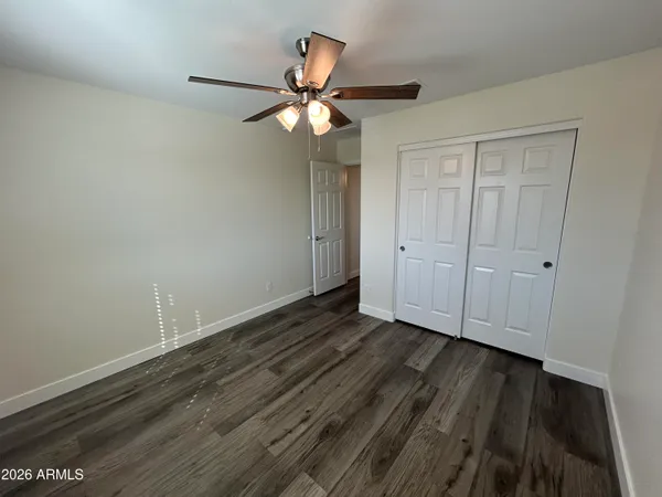 a view of an empty room with wooden floor and a ceiling fan