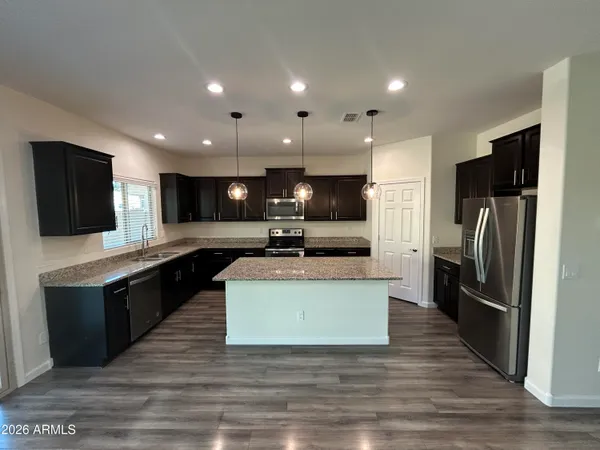 a large kitchen with stainless steel appliances kitchen island granite countertop a large counter top and a stove top oven