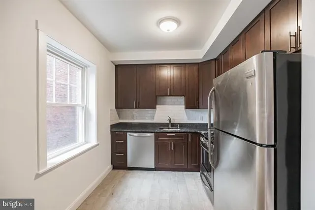 a kitchen with stainless steel appliances granite countertop a refrigerator a sink and a stove