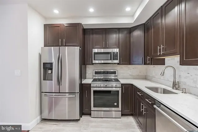 a kitchen with stainless steel appliances granite countertop a refrigerator a stove a sink and a microwave