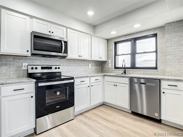 a kitchen with granite countertop a stove a sink and a microwave