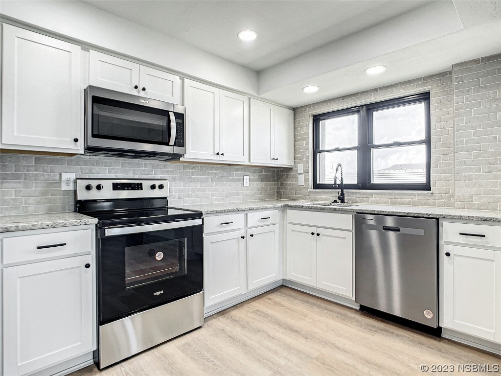 4435 South Atlantic Avenue, Unit 311 Ponce Inlet, FL 32127 - Photo 11 of 44 a kitchen with granite countertop a stove a sink and a microwave